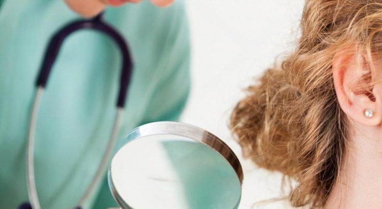 Dermatologist examining a mole on a patient's shoulder with a magnifying glass during a skin check